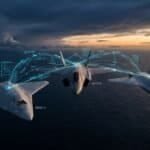 A dramatic, cinematic aerial scene depicting two sleek, futuristic unmanned combat aircraft flying in tight formation alongside a crewed stealth fighter jet over a vast Indo-Pacific ocean expanse at dusk. The autonomous wingman aircraft are angular, low-profile and grey, with no cockpits, featuring subtle sensor arrays and weapons bays. Glowing digital data streams and tactical network overlays connect the aircraft visually, suggesting AI-driven communication and mission coordination. The sky transitions from deep blue to amber on the horizon, with distant storm clouds suggesting a contested, high-stakes environment. The mood is tense, technological and forward-looking. Below, a vast dark ocean stretches to the horizon, emphasizing extreme operational range. The overall aesthetic is realistic military aviation concept art, editorial-quality, high-detail, cinematic lighting, with a cool blue and steel color palette punctuated by warm sunset tones.